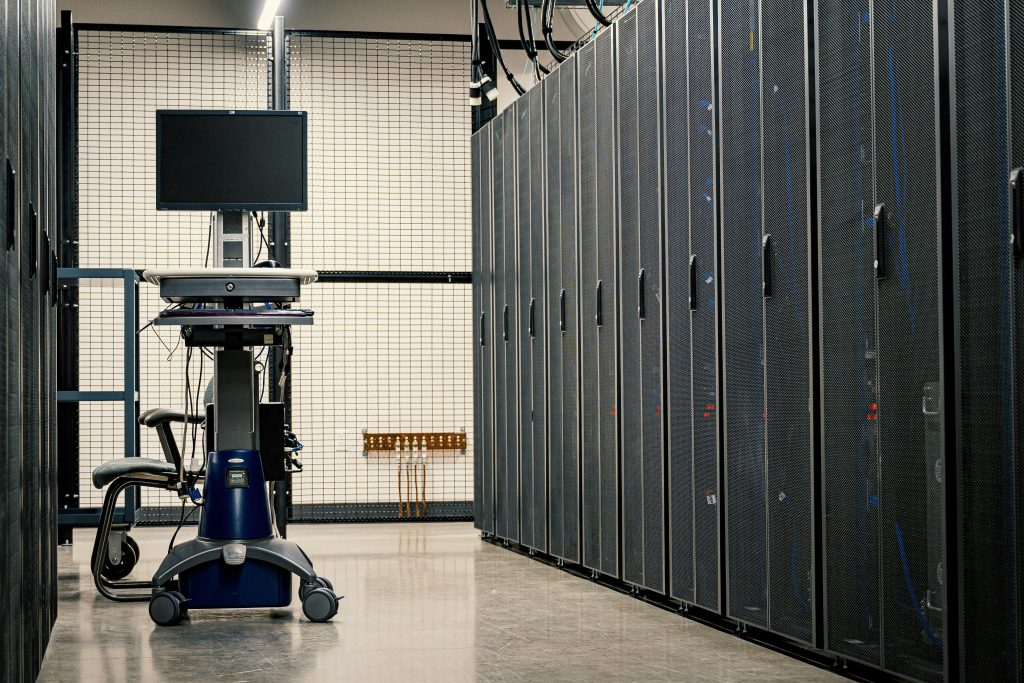 pexels-photo-4597280-4597280 Contemporary computer on support between telecommunication racks and cabinets in modern data center
